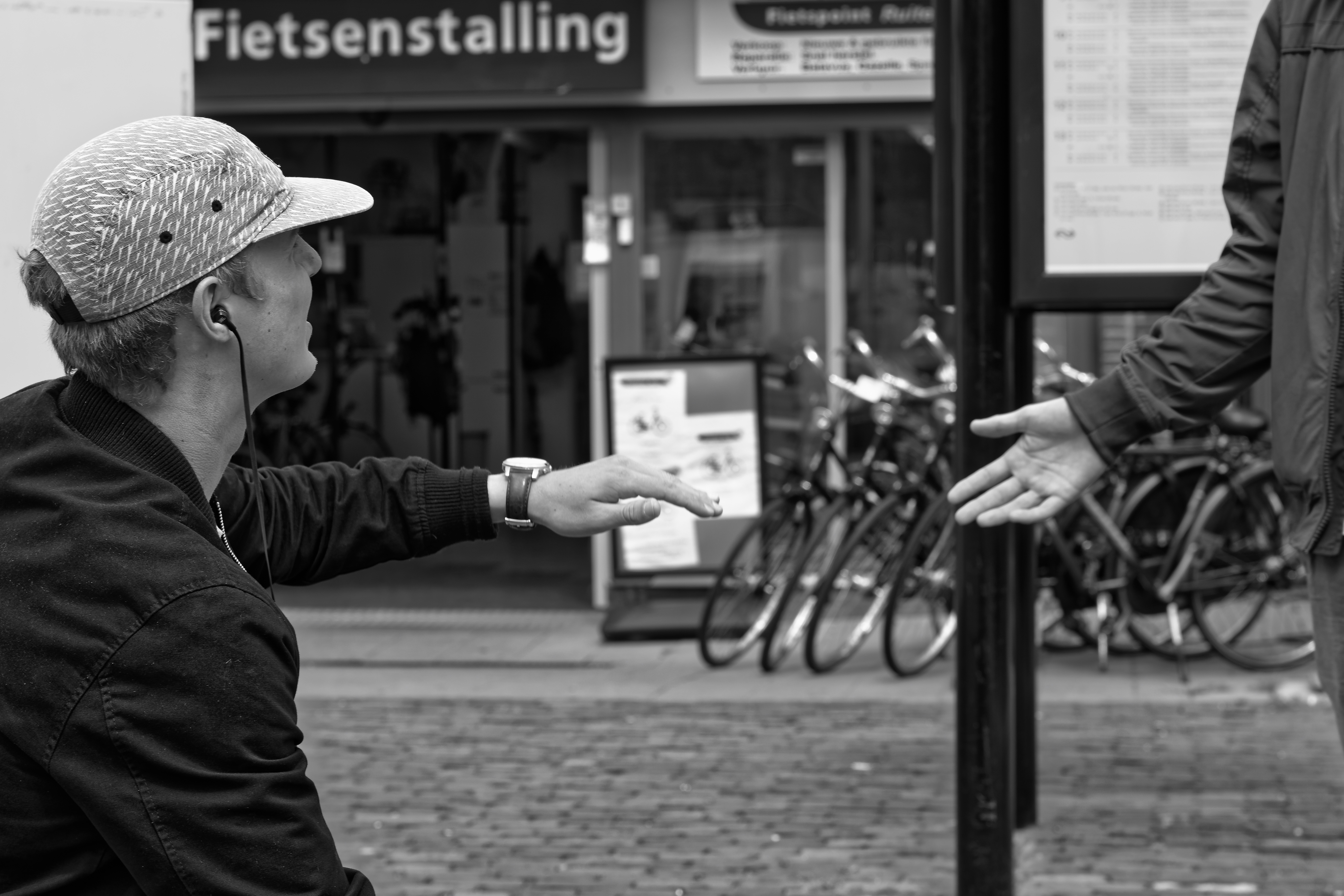 Two people reaching to shake hands across a street, past a bicycle-storage sign