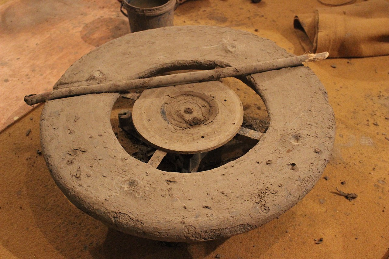A potter's wheel at rest, a turning stick laid across it